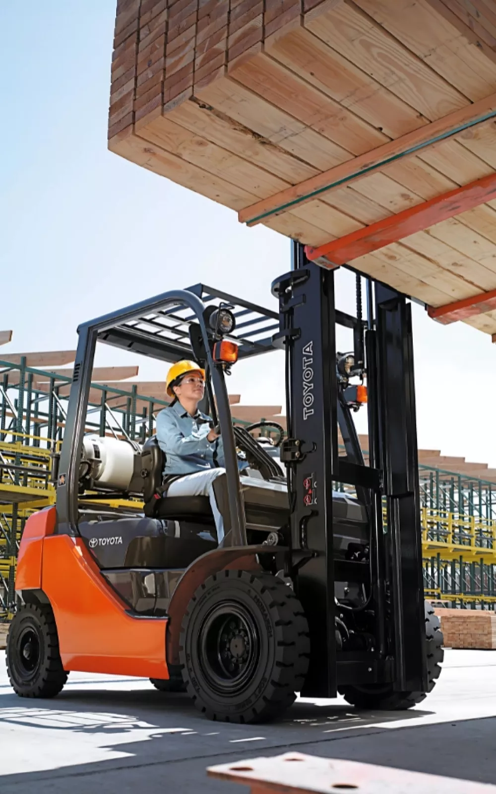 A forklift operator lifting lumber with a Toyota pneumatic tire forklift.
