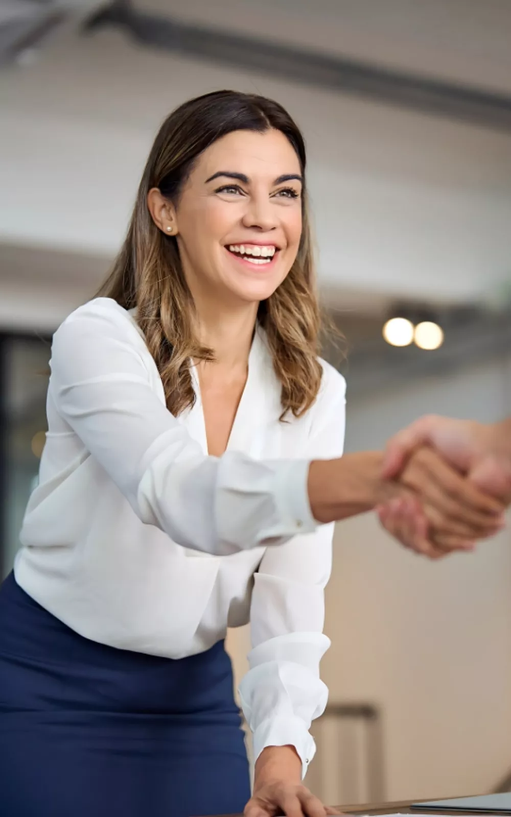 Woman shaking hands with another associate at her workplace.