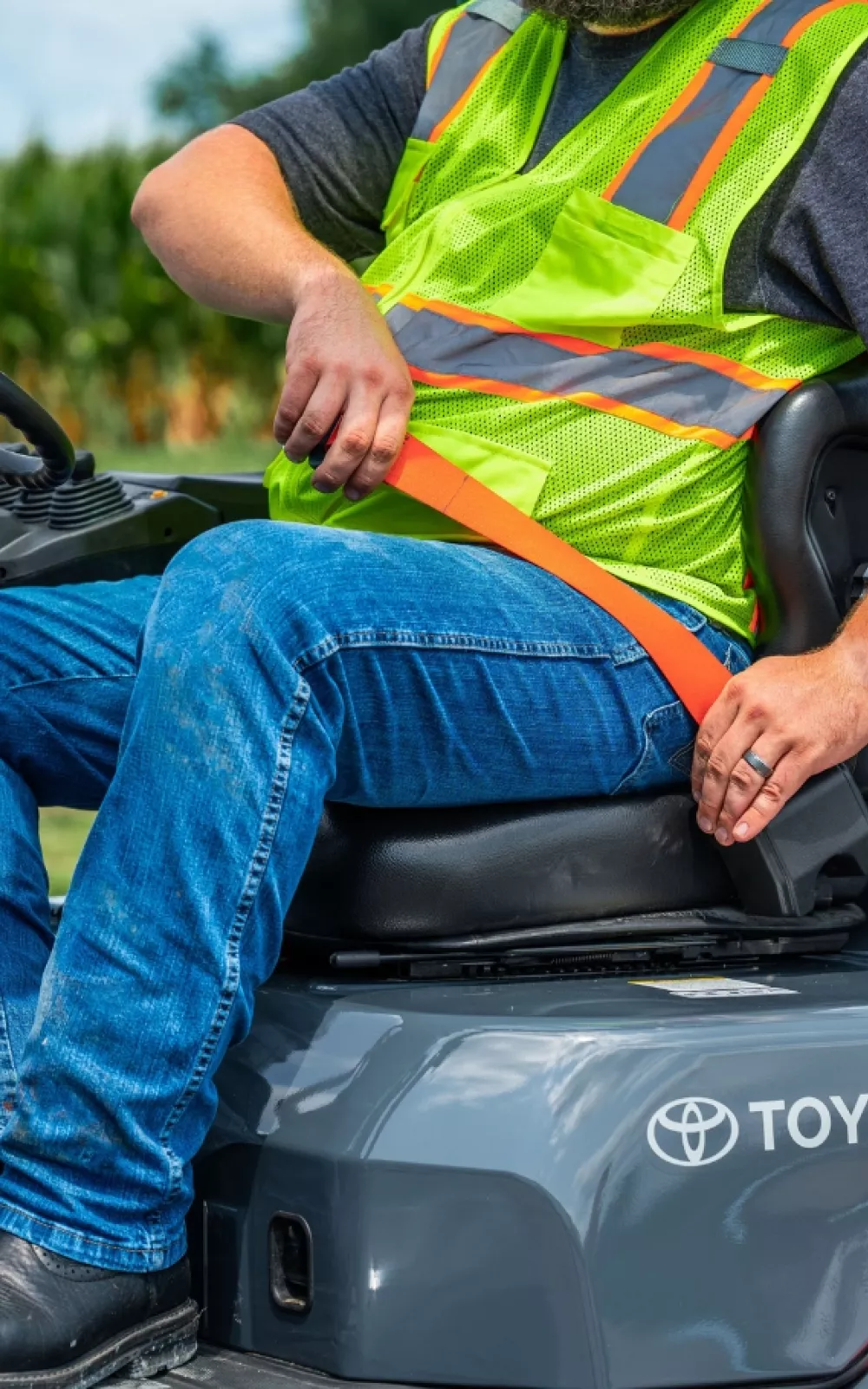 Forklift operator sitting on a Toyota forklift putting on a seatbelt.