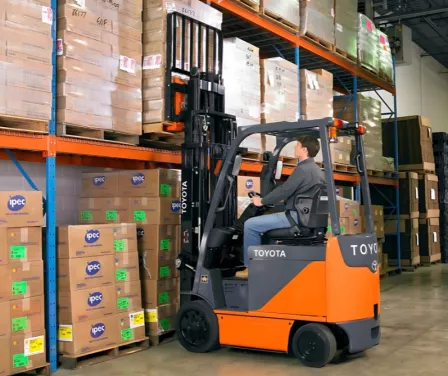 Toyota electric forklift and operator removing product from pallet racking.