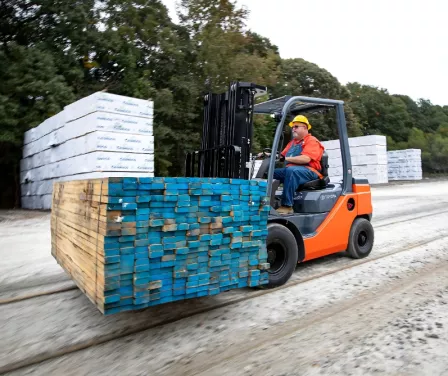 Pneumatic Toyota forklift with forklift operator moving lumber in an outdoor application.