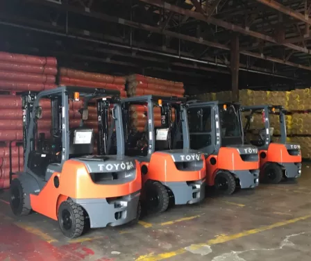 Toyota forklifts sitting in a warehouse near stacked product.