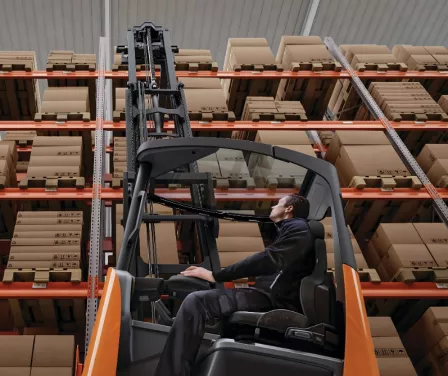 Forklift operator looking up to place product on pallet racking with a Toyota forklift.
