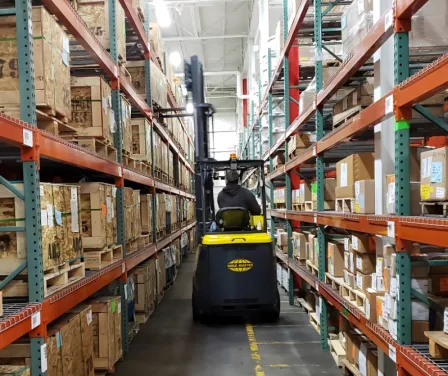 Aisle Master very narrow aisle forklift operating between pallet racking.