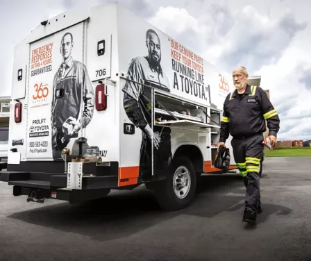 Toyota service technician next to a vehicle at customer site to perform forklift service.