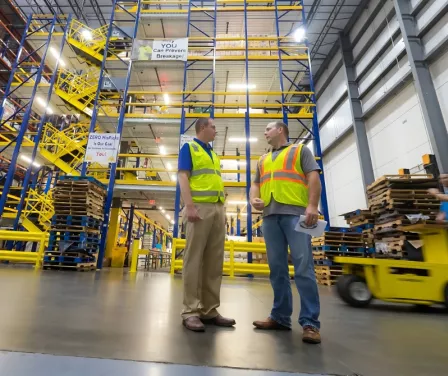 Warehouse associates speaking to one another in a warehouse with automation technology.