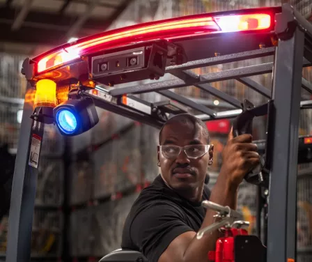 Forklift operator driving a Toyota forklift with safety-enhanced parts and accessories.