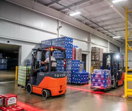 Toyota electric forklifts loading beverage products onto a trailer.