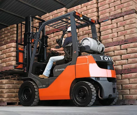 Pneumatic Toyota forklift rental with operator stacking product on the warehouse floor.