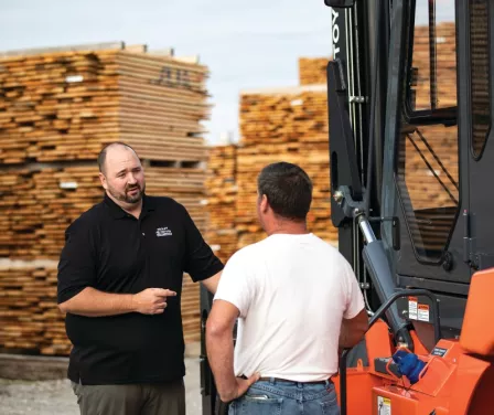 Sales consultant and customer discussing forklift maintenance programs.