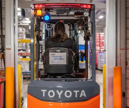 Toyota electric forklift driving through doorway of cold storage facility.