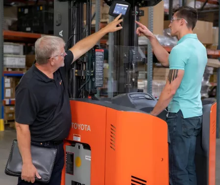 Toyota sales consultant doing a walk-around forklift demo with a customer.