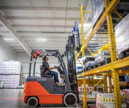 Forklift operator using Toyota forklift to unload product from pallet racking.
