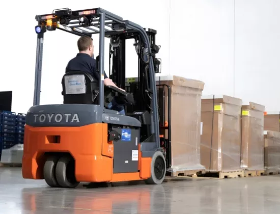 Forklift operator picking up product with a Toyota 3-Wheel electric forklift.