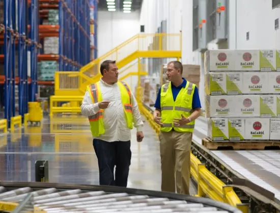 Sales consultant and customer walking through warehouse using a conveyor and automation.