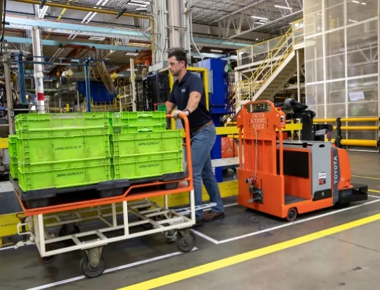 Warehouse associate loading product on a Toyota automated guided vehicle.