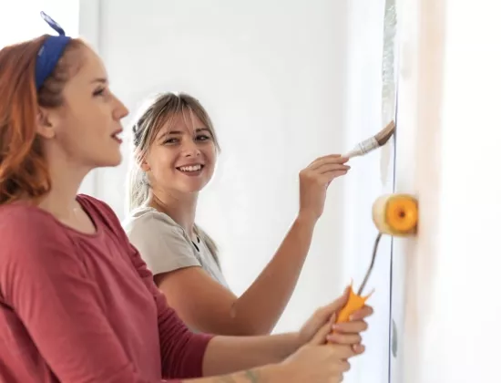 Women volunteering at community organization and painting walls.