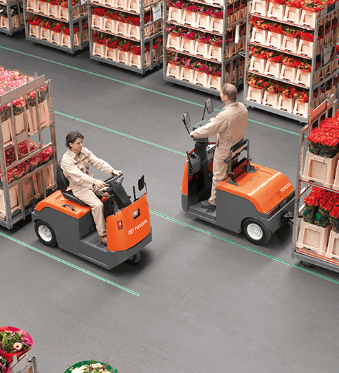 two ProLift Toyota employees driving mid tow tractors in a warehouse