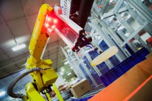 yellow picking robot grabs individual product from the conveyor system to be packaged.