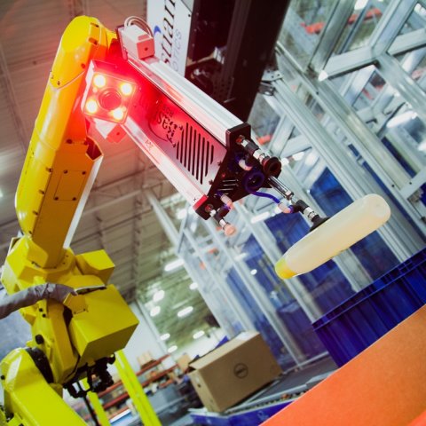 yellow picking robot grabs individual product from the conveyor system to be packaged.