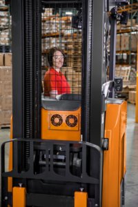 Woman safely operating forklift with safety glasses